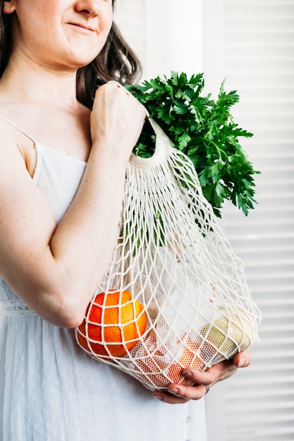 woman holds a bag with food fresh vegetables and fruit