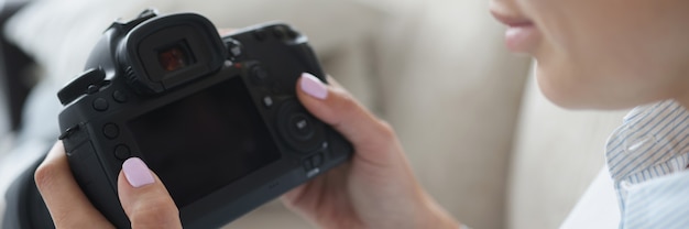 Woman holds black professional camera in her hands