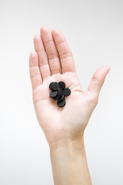 a woman holds a black sorbent pills. detox concept