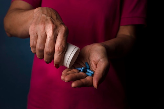 A woman holds blue pills in her hand against a blue background Medical supplies