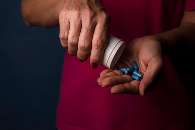 A woman holds blue pills in her hand against a blue background Medical supplies