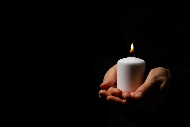 Woman holds candle on black