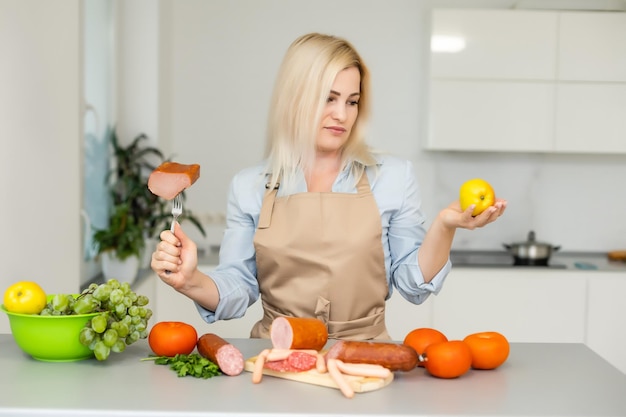 woman holds and chooses between meat and apple