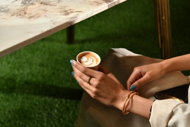 A woman holds a cup of coffee with latte art on it.