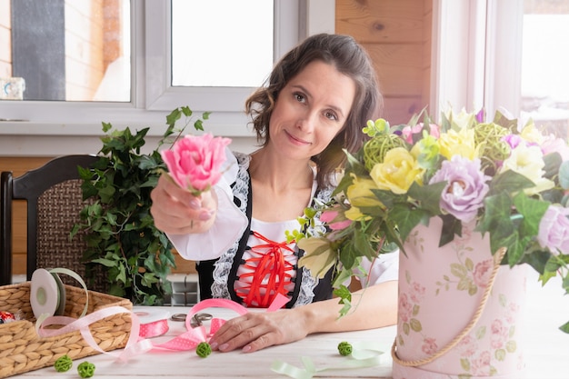 A woman holds a flower in her hands . Plants made of artificial materials made by a florist for design.