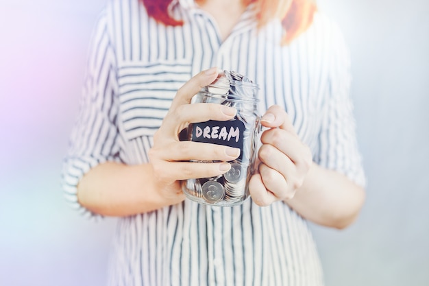 Photo woman holds glass jar of coins for her dream bottle with savings financial for entertainment and lei...