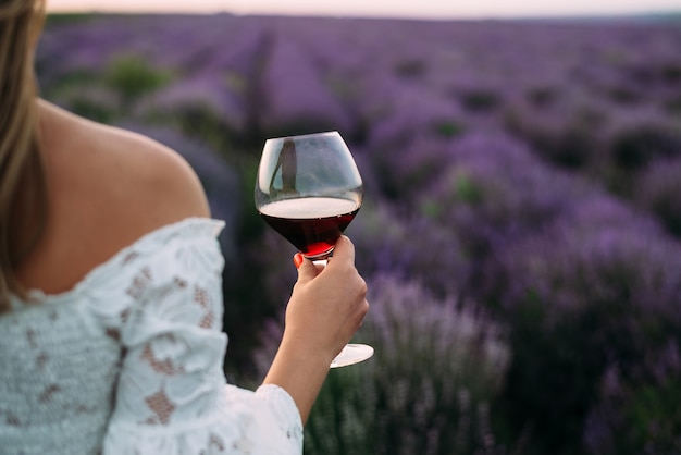 Woman holds a glass of wine in lavender field