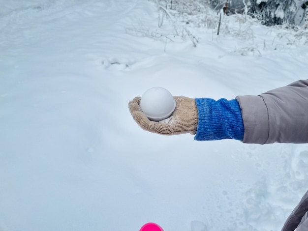 A woman holds in her hand an even snowball made snowball maker