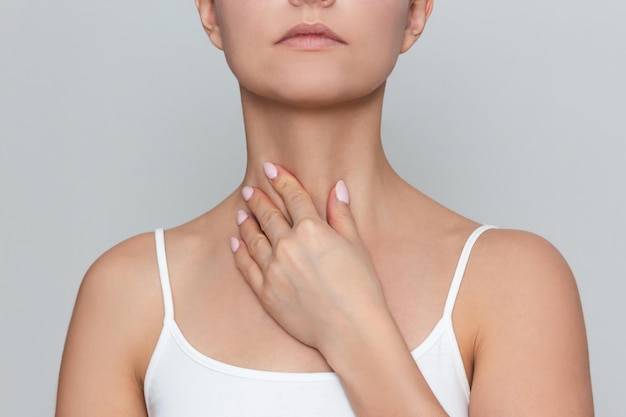 Photo a woman holds her hand on her neck experiences pain when swallowing loss of voice thyroid disease