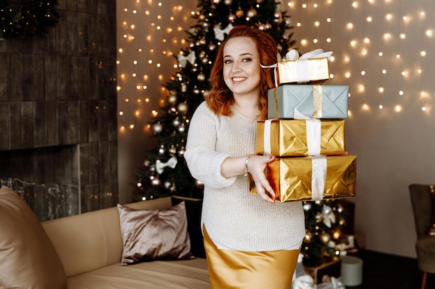 woman holds in her hands Christmas gifts in beautiful gold boxes