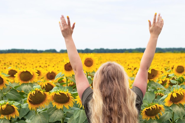 Woman holds her hands up against sunflower field Beauty in nature Selective focus