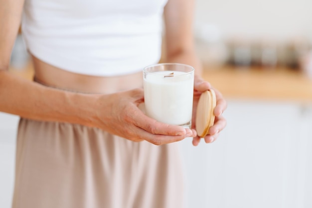 Woman holds in her Hands White Candle with Wooden Lid Blurred Background