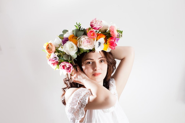 Woman holds her head with art flowers wreath. Natural make up and hairstyle