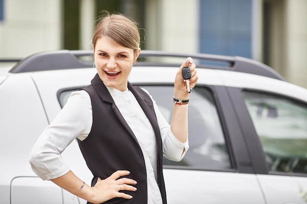 A woman holds the keys to a new car and smiles at the camera Office worker delivery female taxi space for text