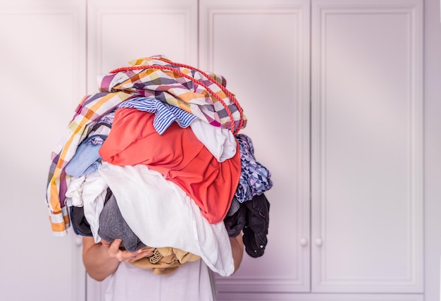 Woman holds a lot of crumpled clothes in her hands white background copypaste