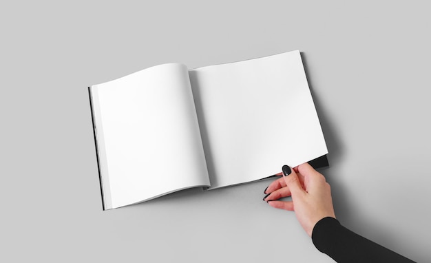 A woman holds a magazine or catalog in a square format with white sheets in her hand Mockup with place for advertising