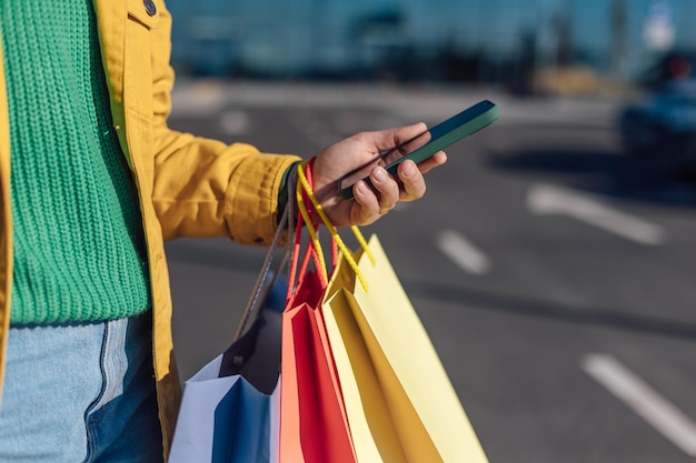 Woman holds martphone and shopping bag with a groceries in hand