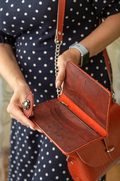 Woman holds an open brown natural leather wallet in her hands