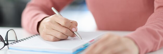 Woman holds pen in her hands and makes notes in diary. Planning and setting daily tasks concept