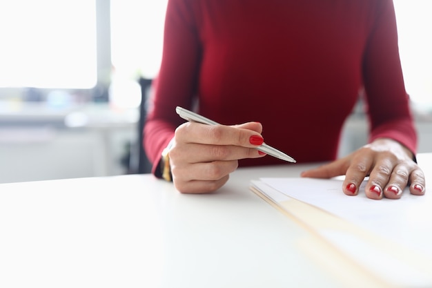 Woman holds pen in her hands and prepares to sign documents