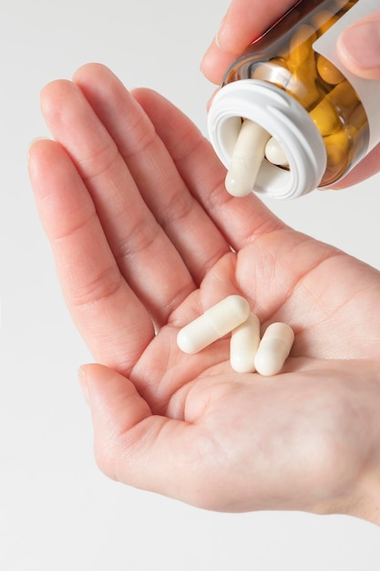 A woman holds pills in her hand pours capsules with painkillers into her hand to get rid of pain tak