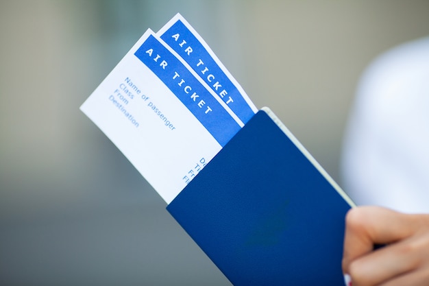 Woman holds plane tickets near airport in passport.