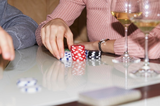 Woman holds playing chips in poker game Cards dices and glasess of champagne Candid moment Poker background lifestyle photography Enjoying the moment digital detox with friends