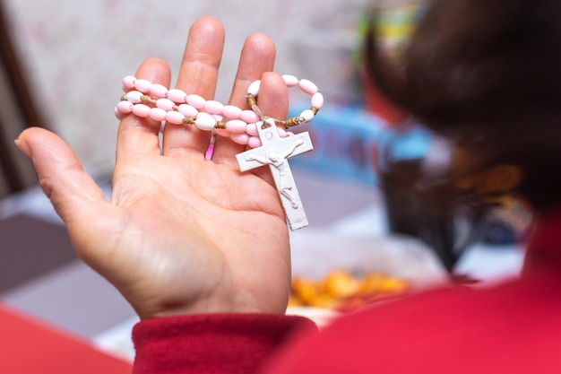 A woman holds a small cross with a necklace in her hand