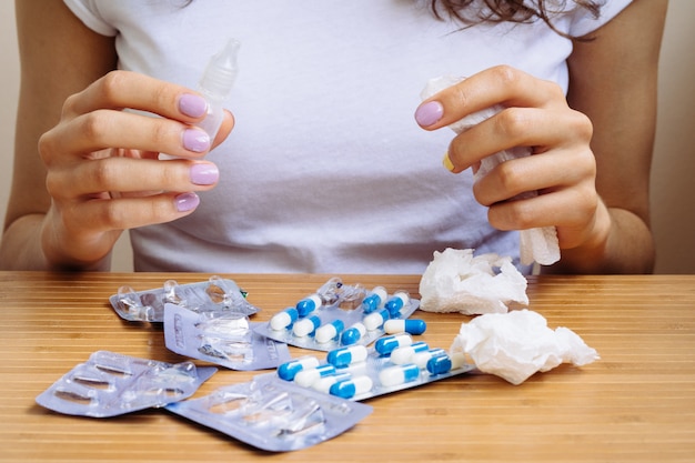 Woman holds a spray for rhinitis and napkins in her hands