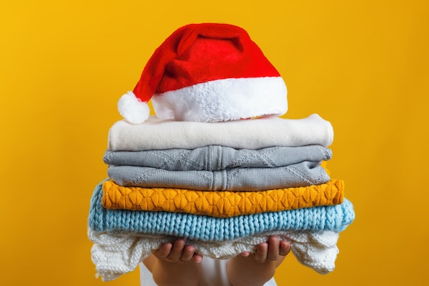 A woman holds a stack of warm knitted clothes