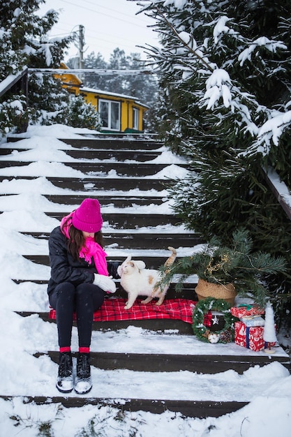 A woman holds and strokes a white and red fluffy cat near a Christmas tree in a basket lights gifts New Year's magical atmosphere of coziness love and warmth