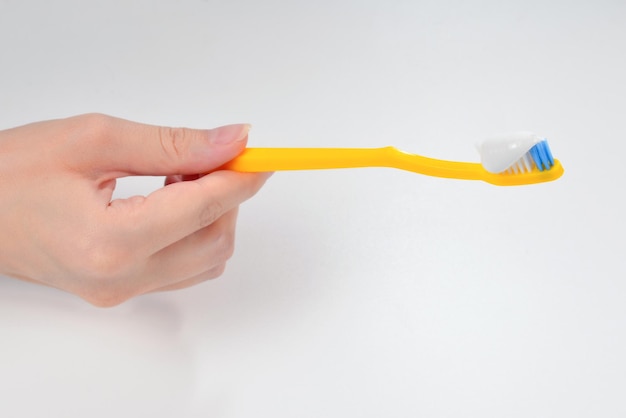 Woman holds toothbrush with toothpaste in her hand isolated on white background