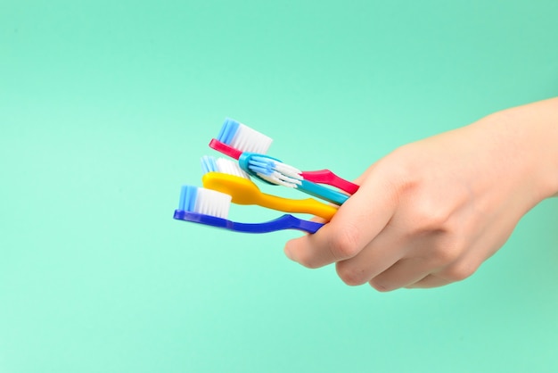 The woman holds toothbrushes in her hand on a green background.