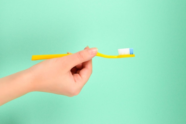 The woman holds toothbrushes in her hand on a green background.