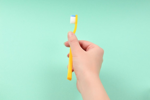 The woman holds toothbrushes in her hand on a green background.