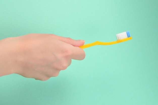 The woman holds toothbrushes in her hand on a green background