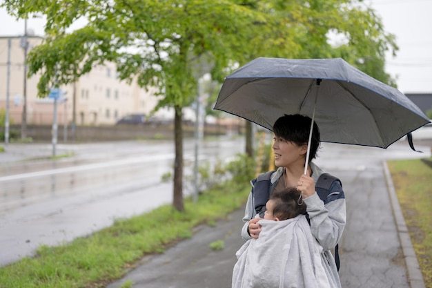 A woman holds an umbrella and walks with her child in the rain.