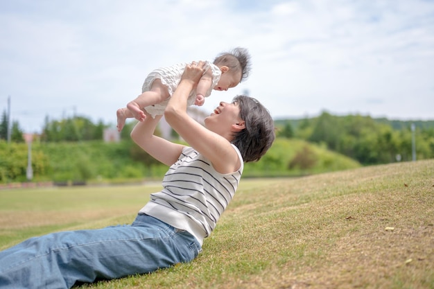 A woman holds up a baby in a park