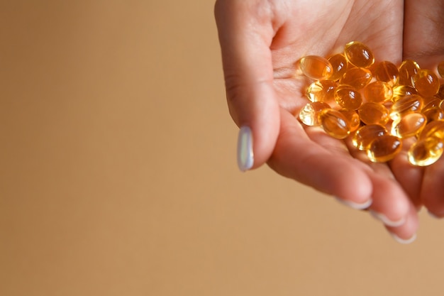 Woman holds vitamin omega-3 capsules or tablets in her palms. The concept of a healthy eating and diet.