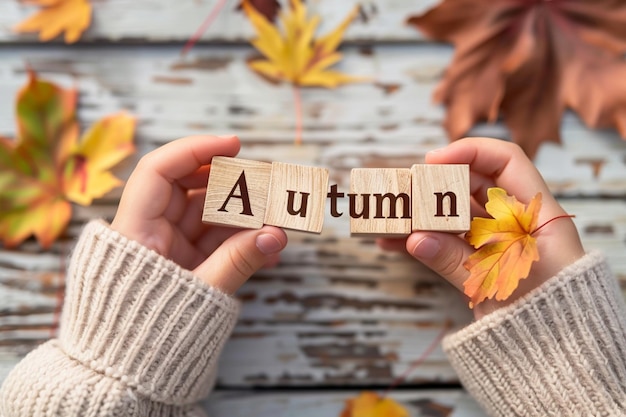 a woman holds wooden blocks with the word autumn written on them