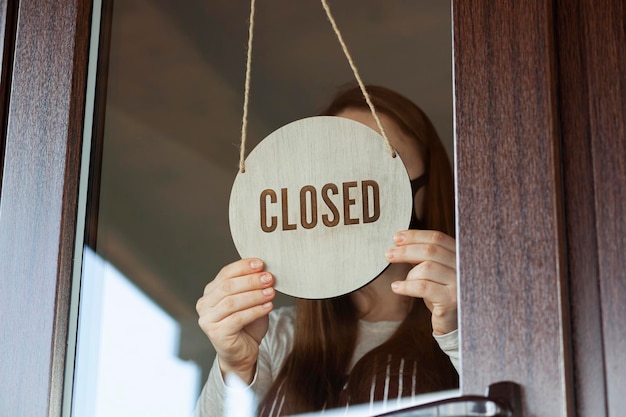 Woman holds the wooden sign with text Closed