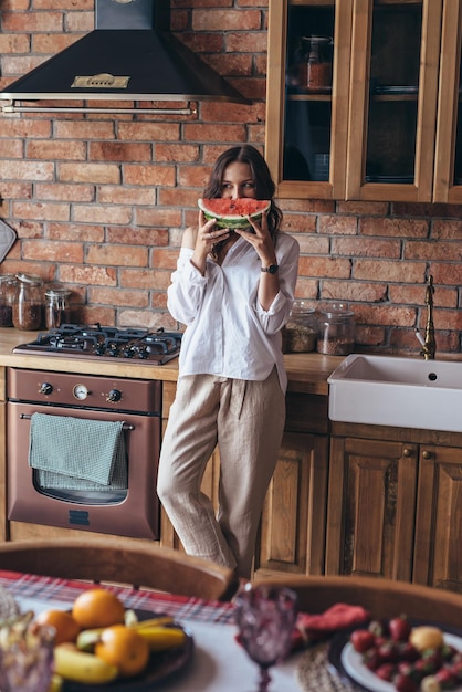 Woman at home eating watermelon in the kitchen