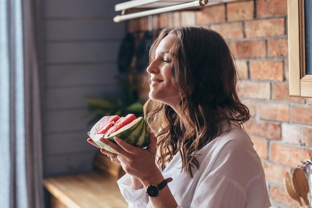 Woman at home eating watermelon in the kitchen