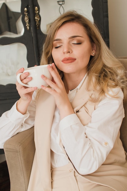 Woman at home with cup of coffee on sofa with closed eyes