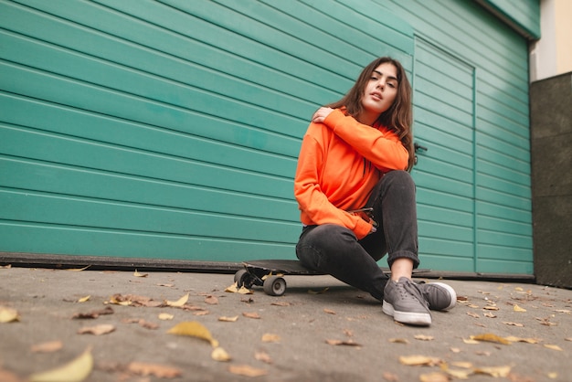 Woman in hoodie stands with a longboard