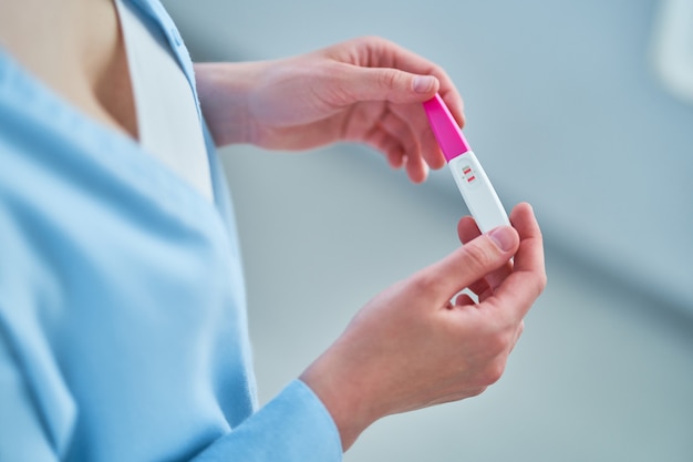 Woman hopes to get pregnant and holds in hands a pregnancy test with two stripes