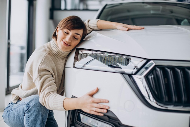 Woman hugging car in a car showroom