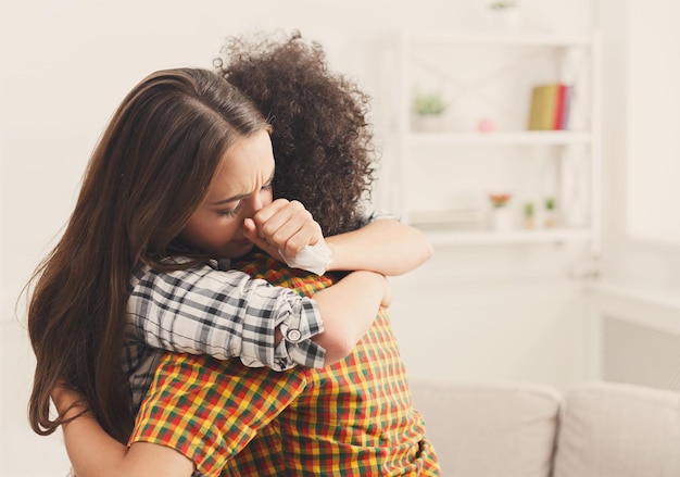 Woman hugging her depressed friend at home