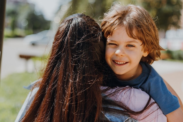 Woman hugs a child boy on the street. mother and son are walking in the park. lifestyle. concept of a happy childhood and motherhood. space for text. High quality photo