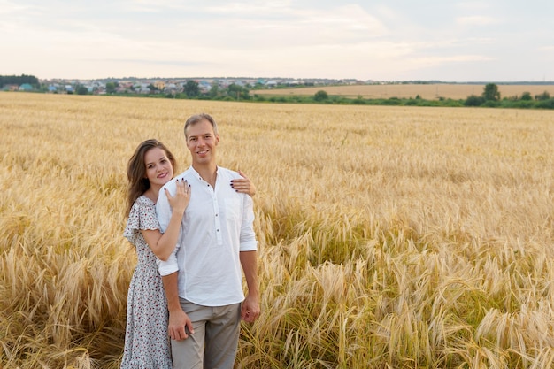 Woman hugs man walking on a wheat field Love couple romantic relationship